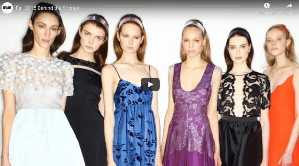 Six women in colorful dresses and headbands pose together against a plain white background.