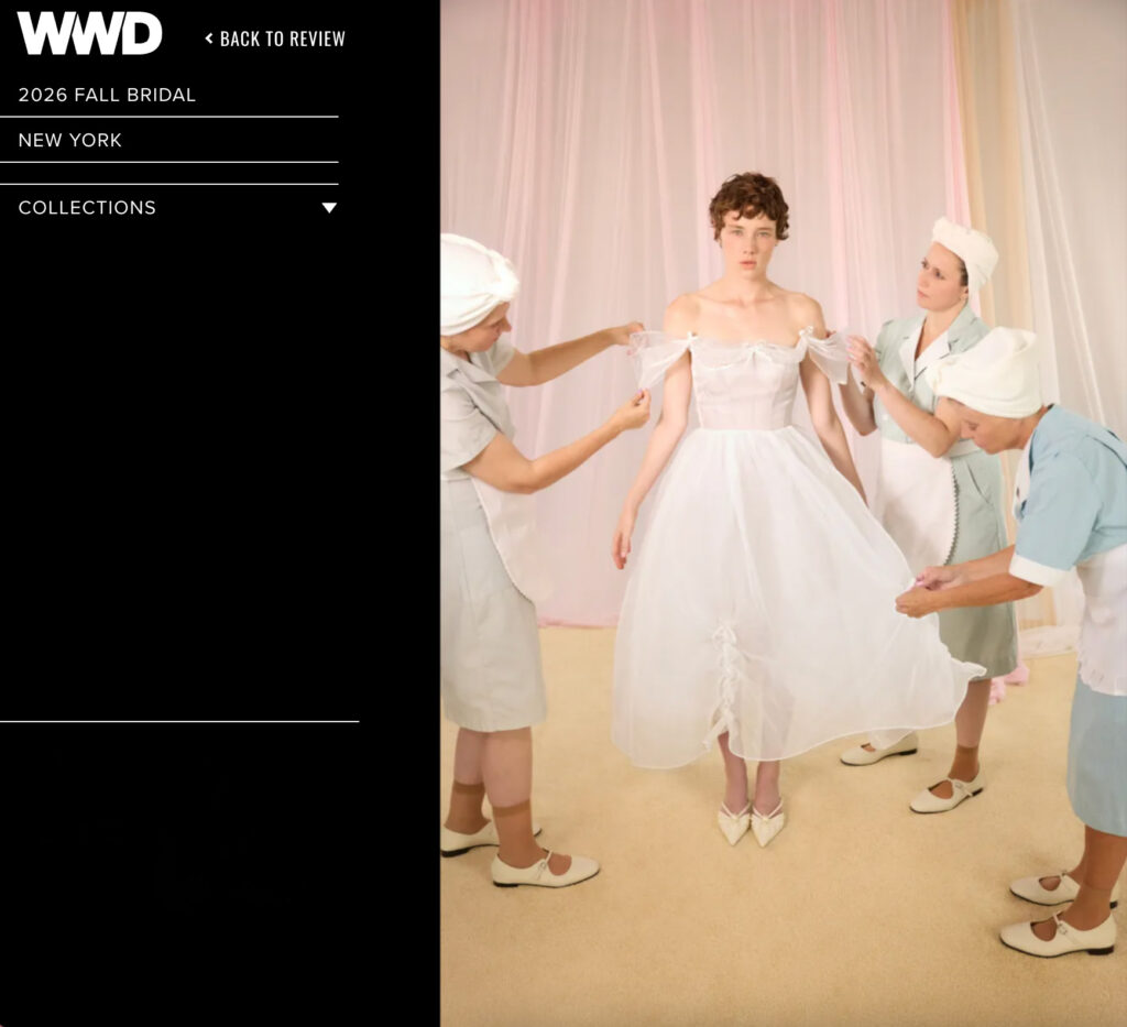 A bride in a white dress is fitted by three women in uniforms in a pastel-colored room.