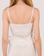 A woman is shown from the back against a plain background, wearing the Cashmere Heart Knit Camisole in Cream. The camisole is complete with satin ribbon bow detailing.