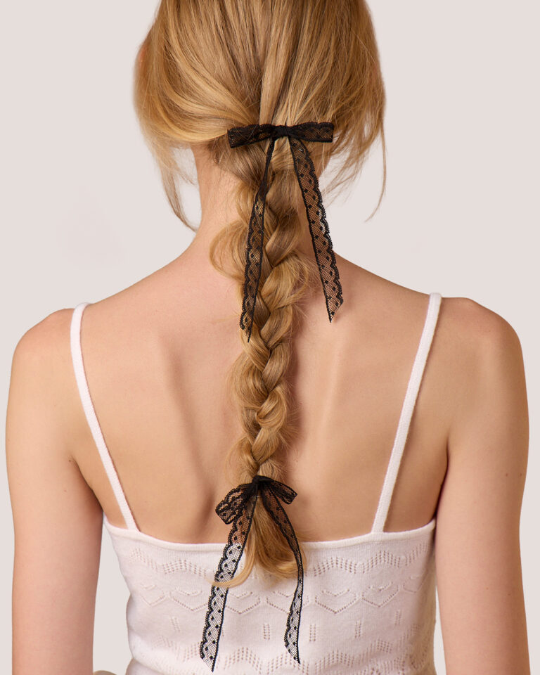 Woman with blonde braided hair, styled with Dot Lace Bow Hairpins in Black and wearing the Cashmere Heart Knit Camisole in Cream, photographed from behind.