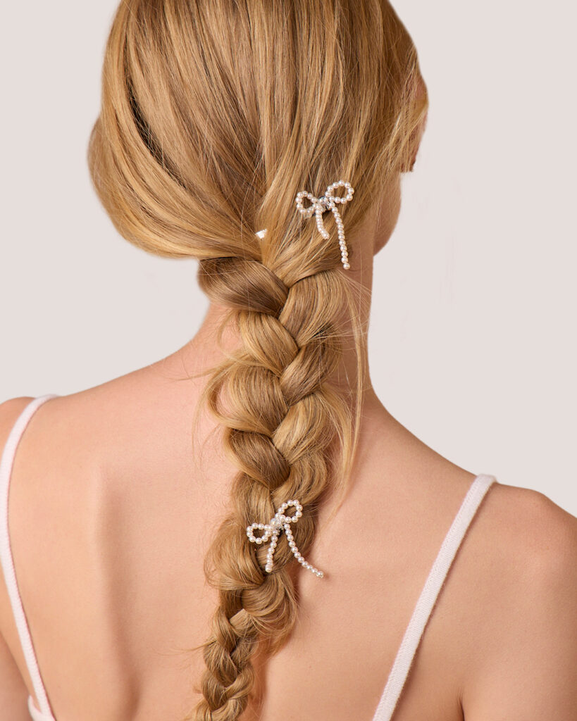 A woman with a braid, seen from behind, wears two Pearl Bow Hairpins as accessories.