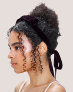 Woman in profile with curly hair, wearing the Velvet Bow Hair Comb in Plum.