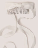 The Velvet Bow Hair Comb in White features a white velvet bow with long ribbons, attached to a silver hair comb and is shown against a pale background.