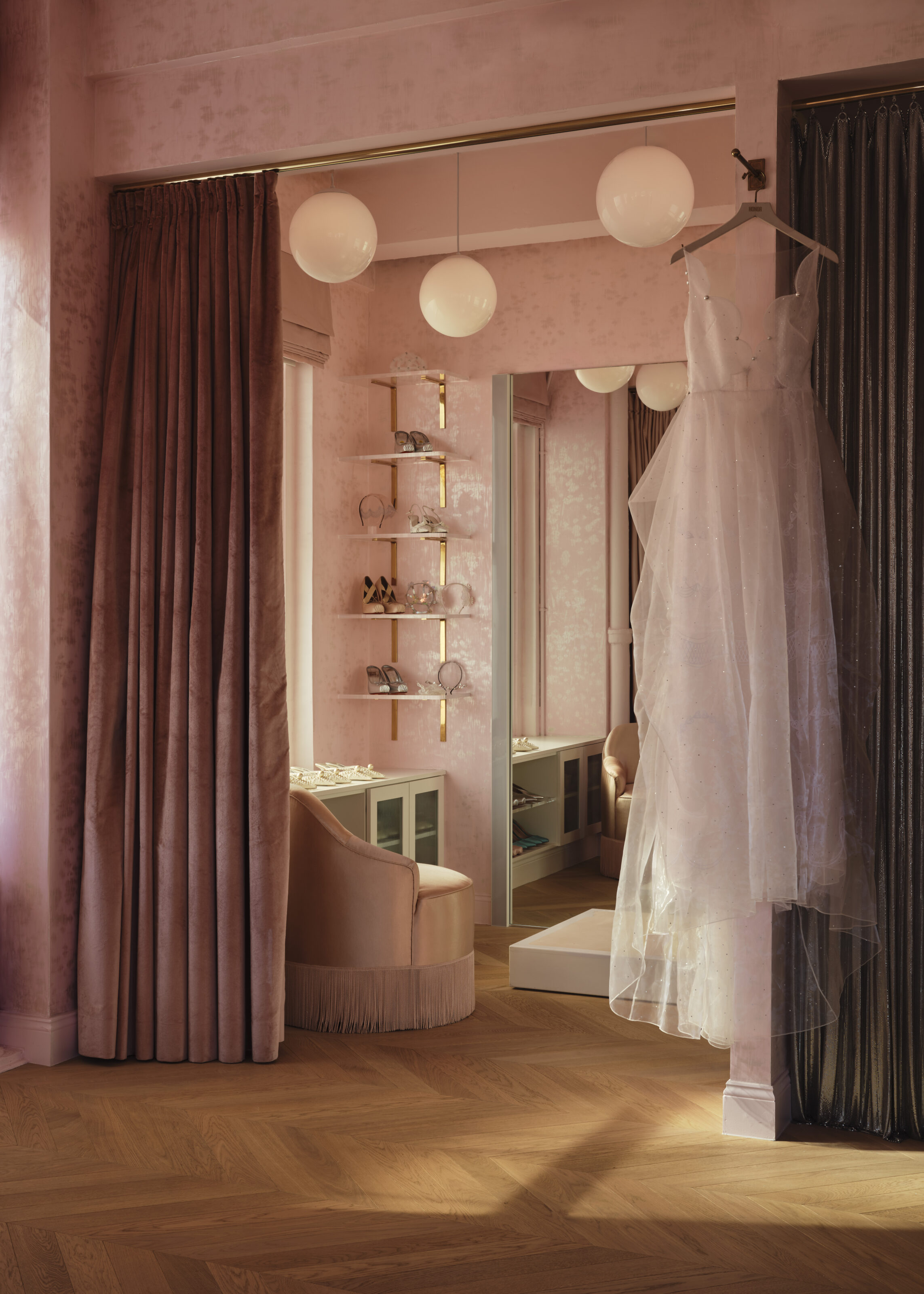 HONOR showroom with pink curtains, a mirrored fitting area and a hanging bridal gown.